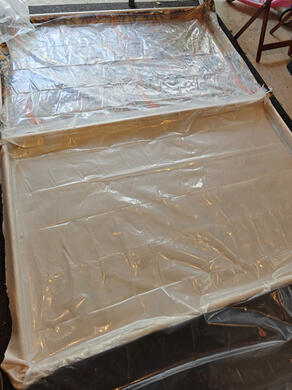 frame with plastic sheeting one wooden flat, on the floor, with cloth stapled across it facing down, and plastic sheeting stapled underneath.